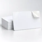 Blank white adhesive PVC cards with a single card in front of a neat stack